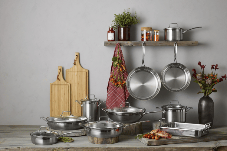 Collection of stainless steel cookware on a wooden surface with a neutral background